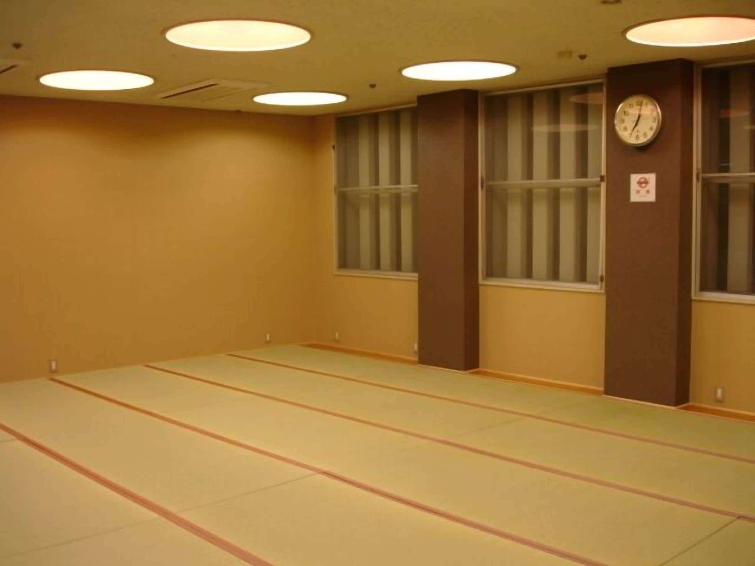 A room with tatami mats, a clock, and a window with blinds.