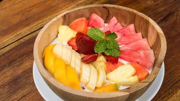 Uma tigela de madeira cheia de frutas fatiadas e uma folha de hortelã sobre uma mesa de madeira.