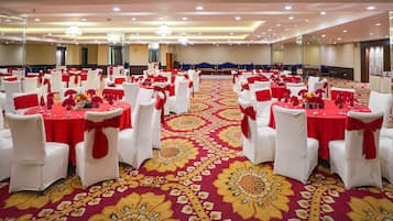 Una sala de banquets amb taules rodones, cadires blanques i estovalls vermells.