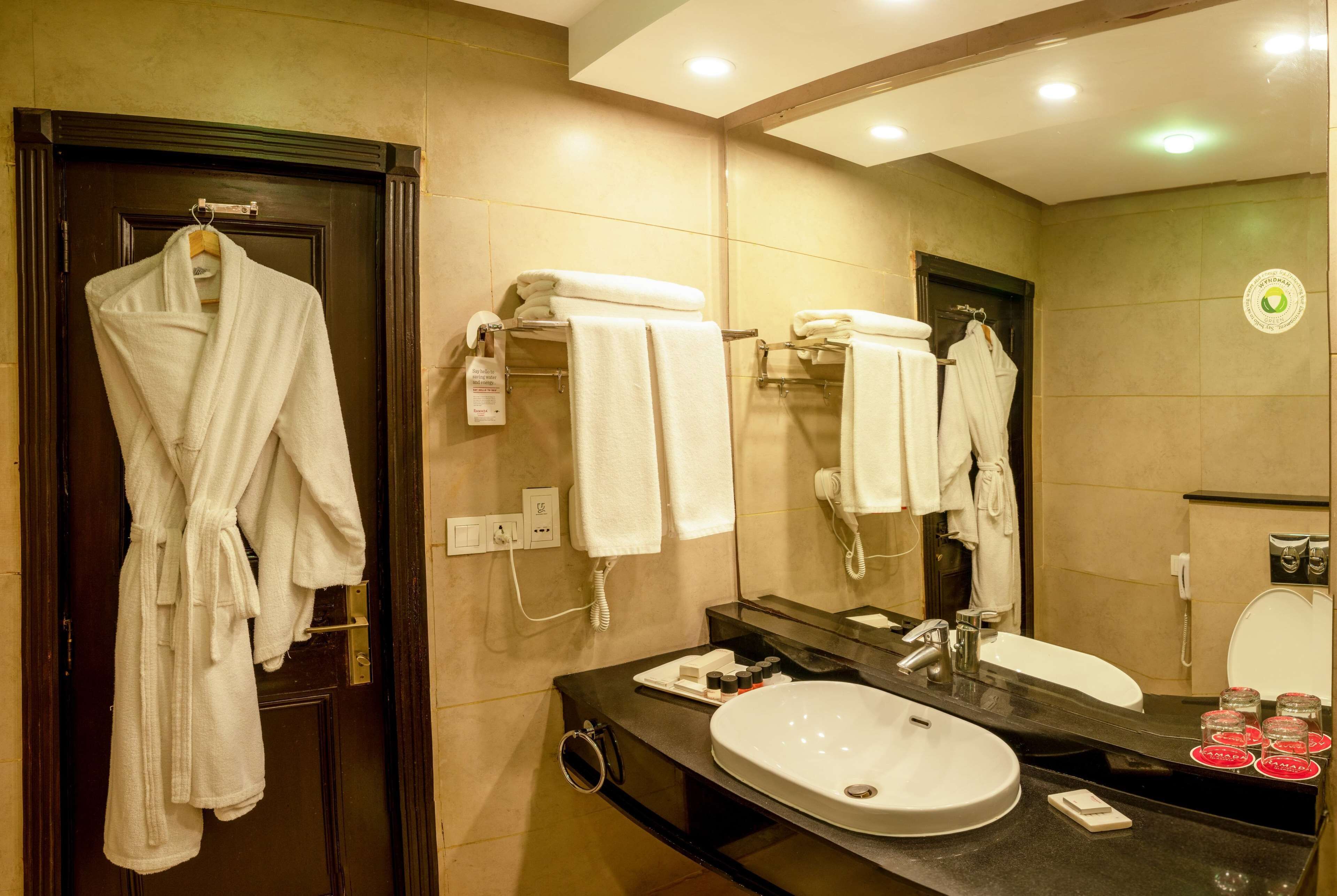 Une salle de bain d’hôtel avec un grand miroir, un lavabo et des serviettes suspendues à un porte-serviettes.