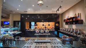 A buffet setup with multiple serving stations, a central serving area, and a patterned floor. - Ramada by Wyndham Islamabad (Islamabad)
