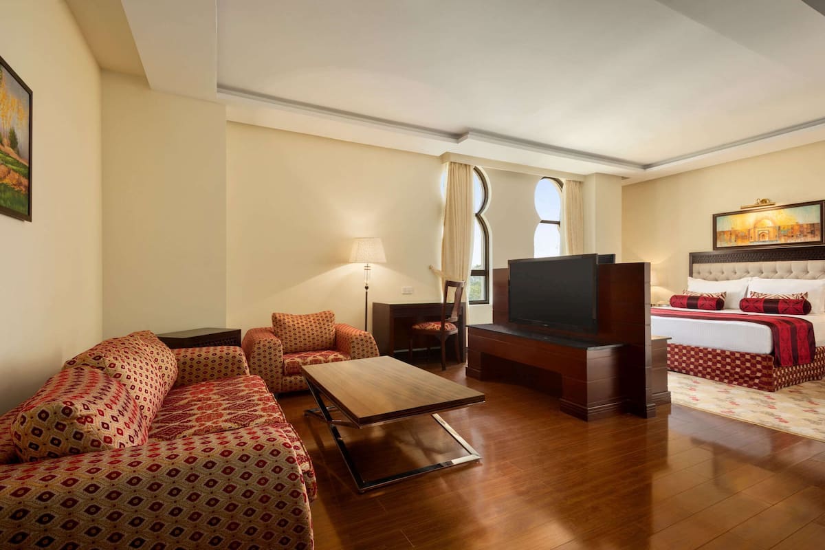 Habitación de hotel con sofá, televisión, cama y escritorio.