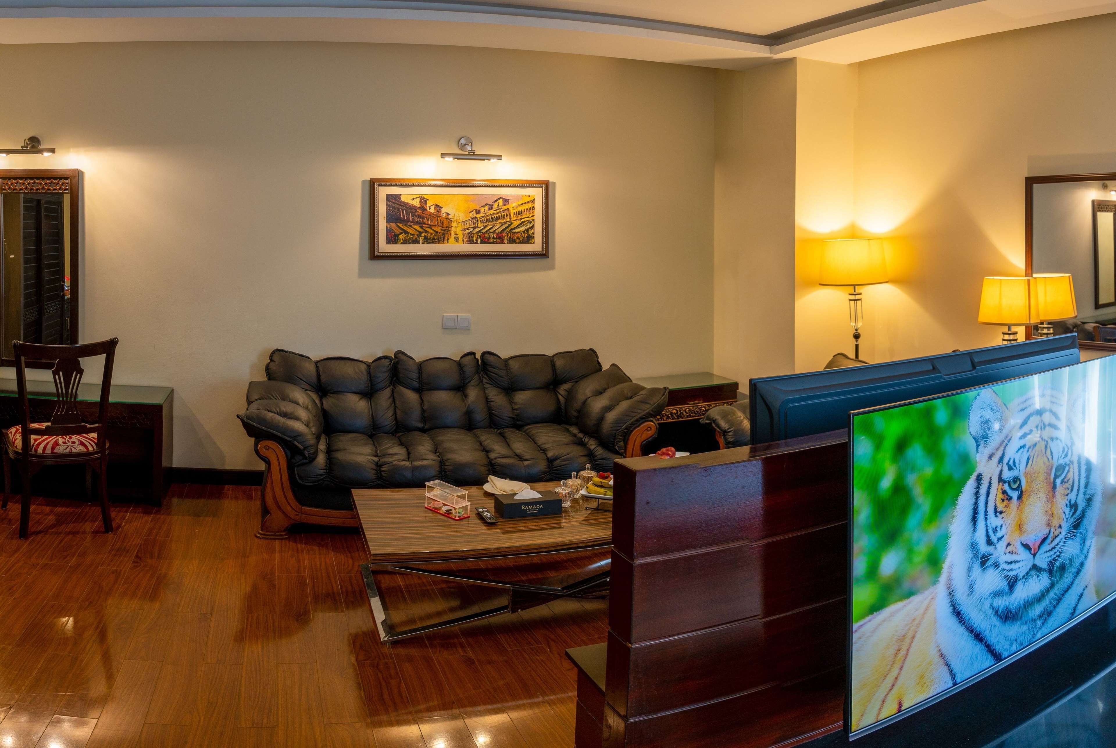 Een woonkamer met een leren bank, een houten salontafel en een flatscreen televisie waarop een tijger te zien is.