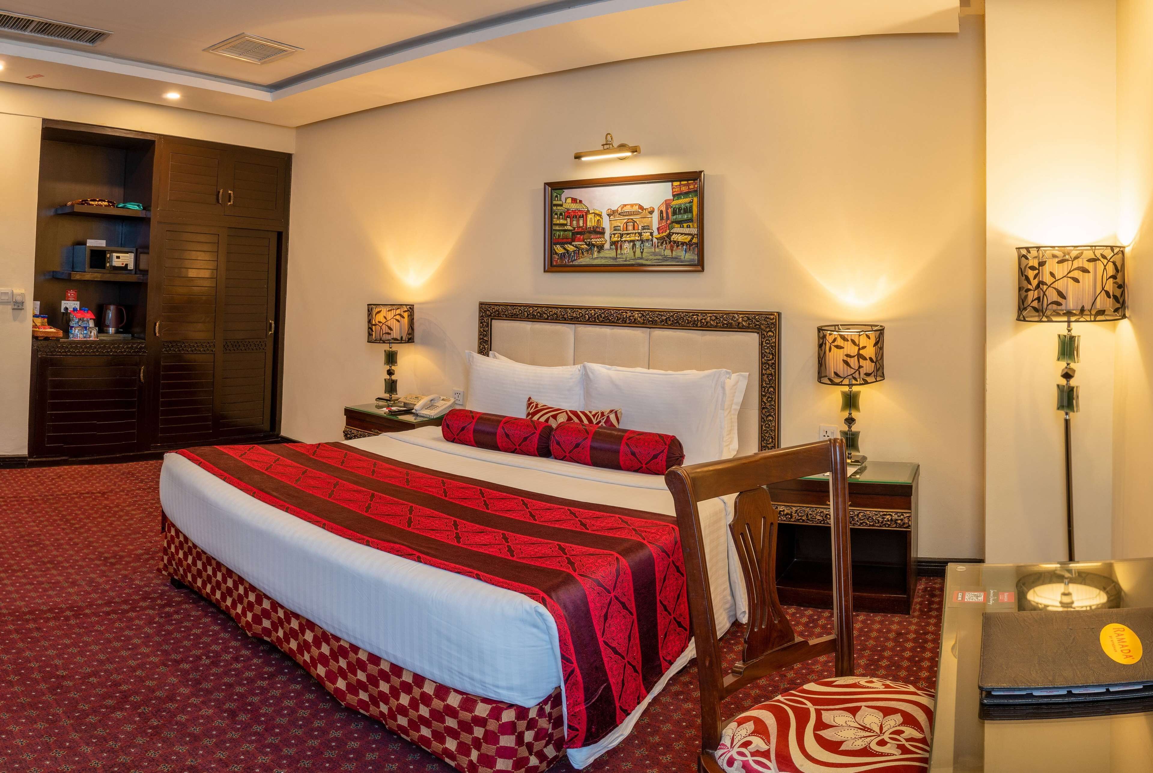 A hotel room with a large bed, a wardrobe, a desk, and a laptop on the desk.