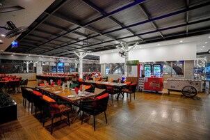 Un restaurante espacioso con techos altos y decoración moderna, que cuenta con varias mesas y sillas, además de un carrito de comida.
