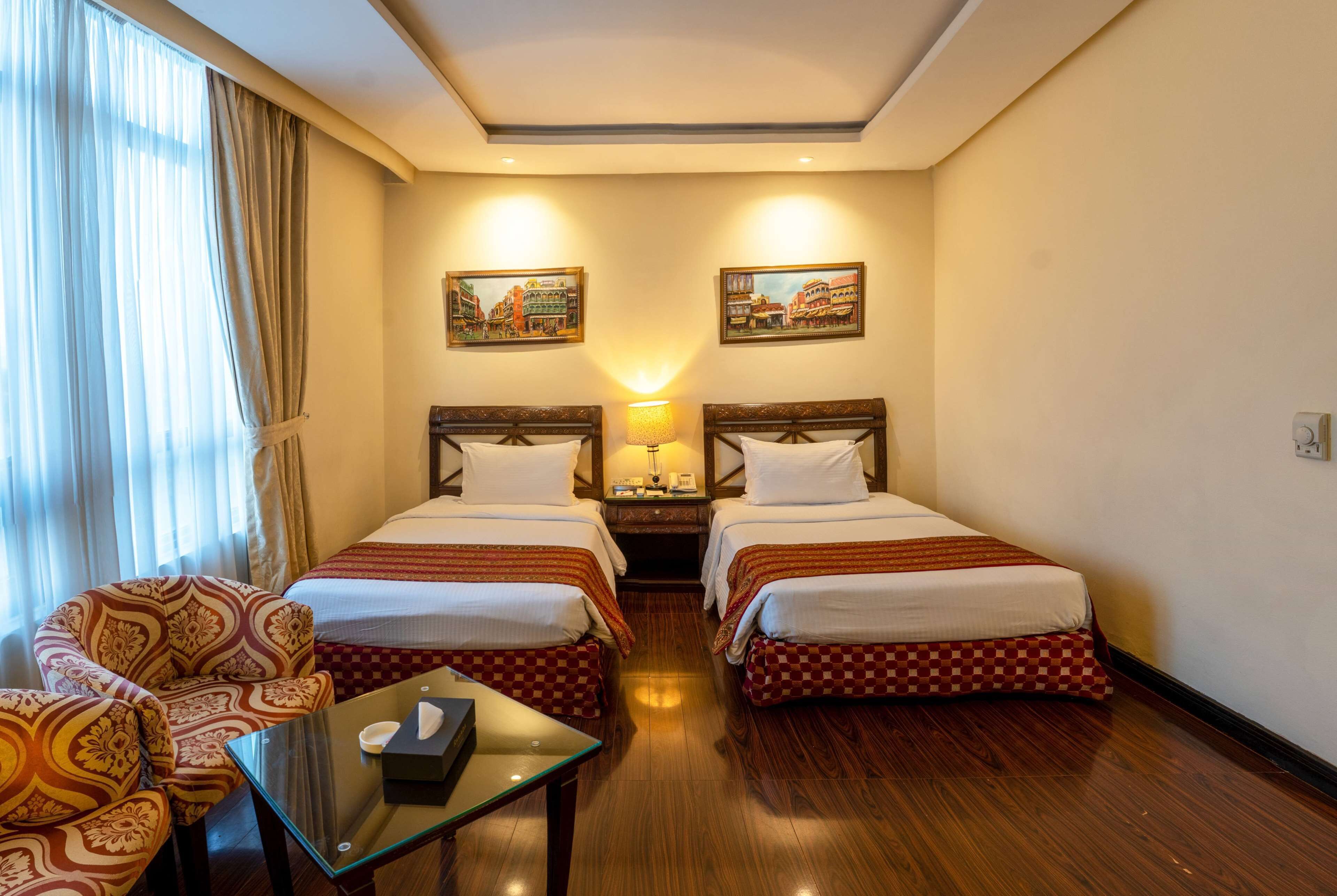 Une chambre d’hôtel avec deux lits, un canapé, une table et une lampe.