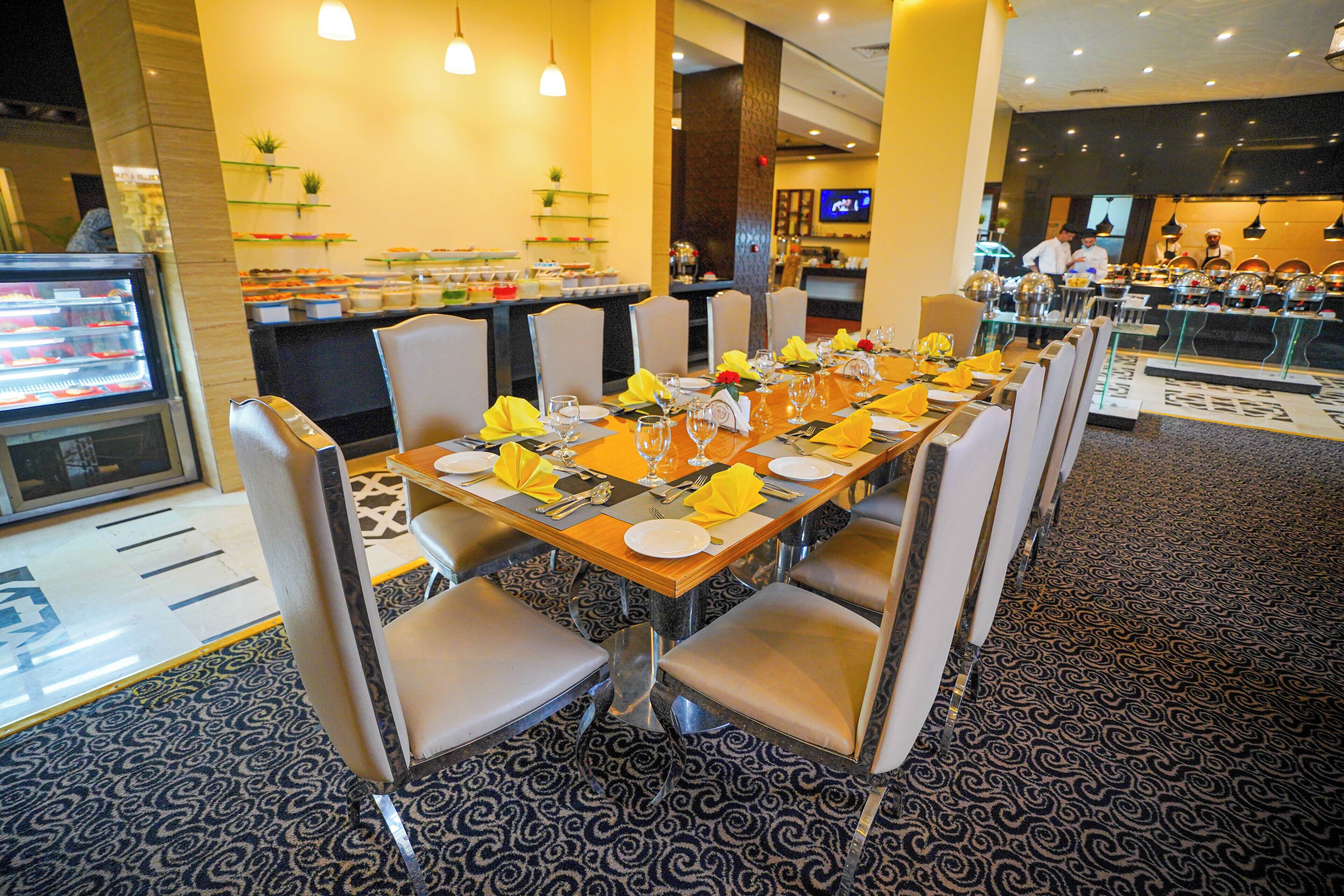 A restaurant with a long dining table set for a meal, surrounded by chairs.