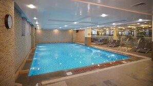 An indoor swimming pool with a no diving sign, surrounded by lounge chairs and exercise equipment. - Ramada by Wyndham Islamabad (Islamabad)