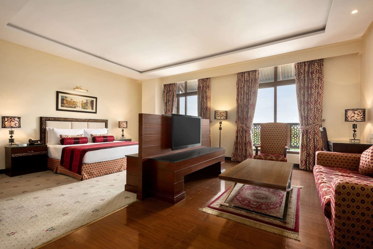 Una habitación de hotel con cama, televisión, sofá y mesa de centro.