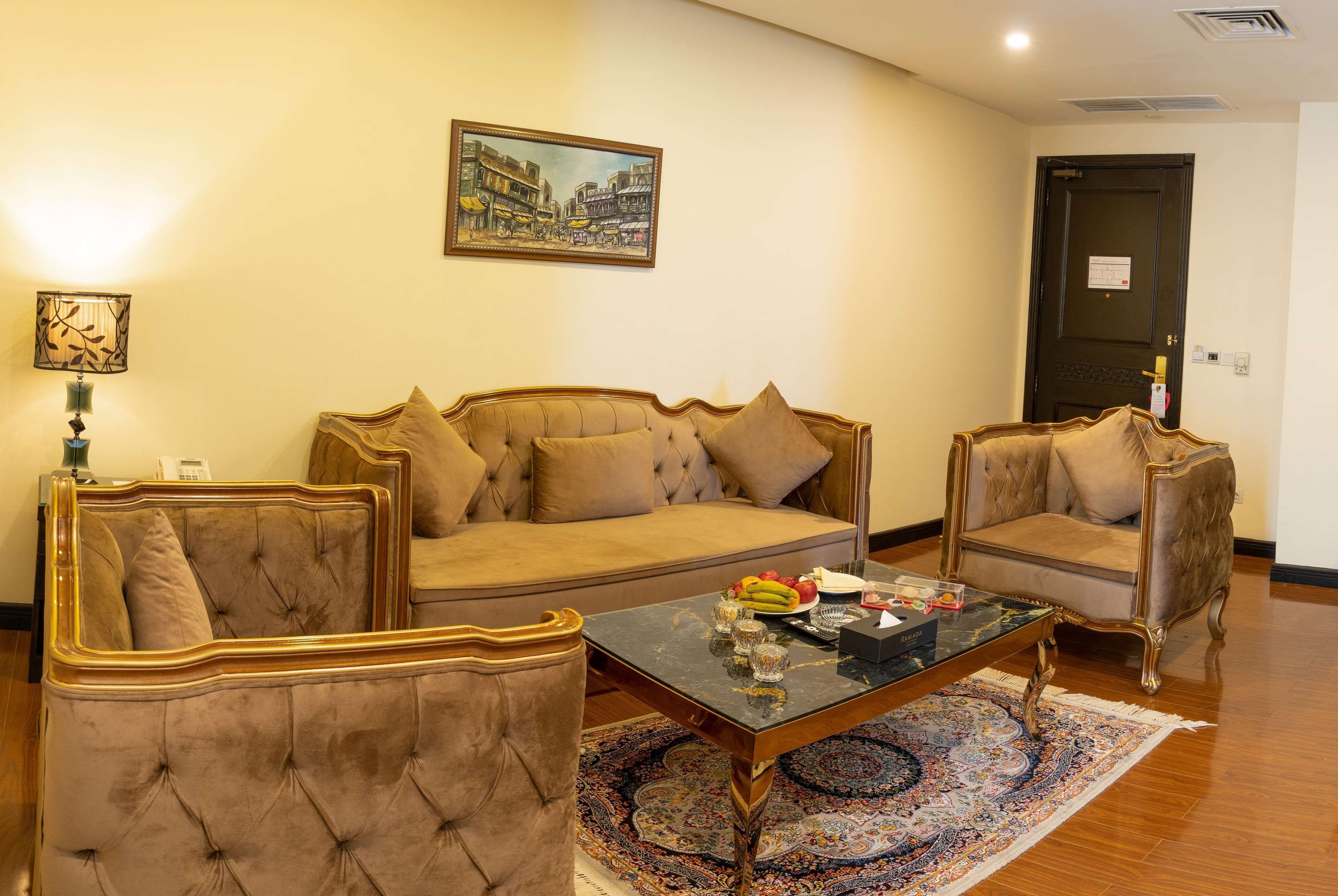 A living room with a sofa, two armchairs, a coffee table, and a patterned rug.