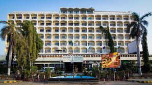 A multi-story hotel with a central courtyard, a fountain, and a sign for a restaurant named Hi-Tea. - Hotel Mehran (Karachi)