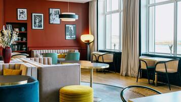 Een modern interieur met een zithoek, een eettafel en een groot raam met gordijnen.
