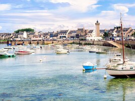 Un port avec des bateaux, un phare et des bâtiments en arrière-plan.