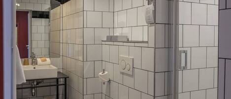 A bathroom with a black and white checkered floor, a glass shower enclosure, a white toilet, and a sink with a mirror above it.