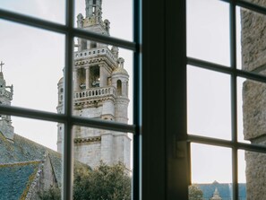 Une vue à travers la fenêtre d’un bâtiment historique, doté d’une tour imposante et de détails architecturaux complexes.