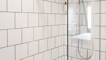 A modern shower area with white tiles and a glass partition.