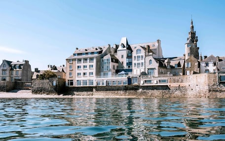 A waterfront building with multiple stories, stone walls, and a prominent tower.