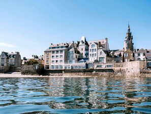 A waterfront building with multiple stories, stone walls, and a prominent tower. - Hotel Mercure Roscoff Bord de Mer (Roscoff)