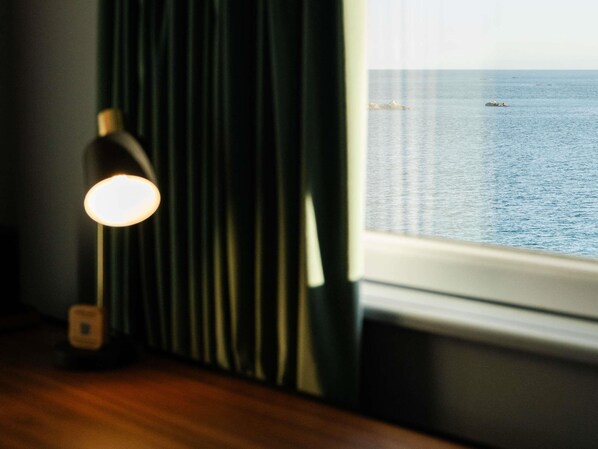 A room with a window, a lamp, and a view of the sea. - Hotel Mercure Roscoff Bord de Mer (Roscoff)