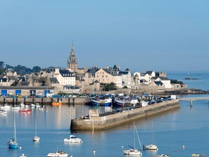 A coastal town with historic buildings, a prominent tower, and a harbor filled with boats. - Hotel Mercure Roscoff Bord de Mer (Roscoff)