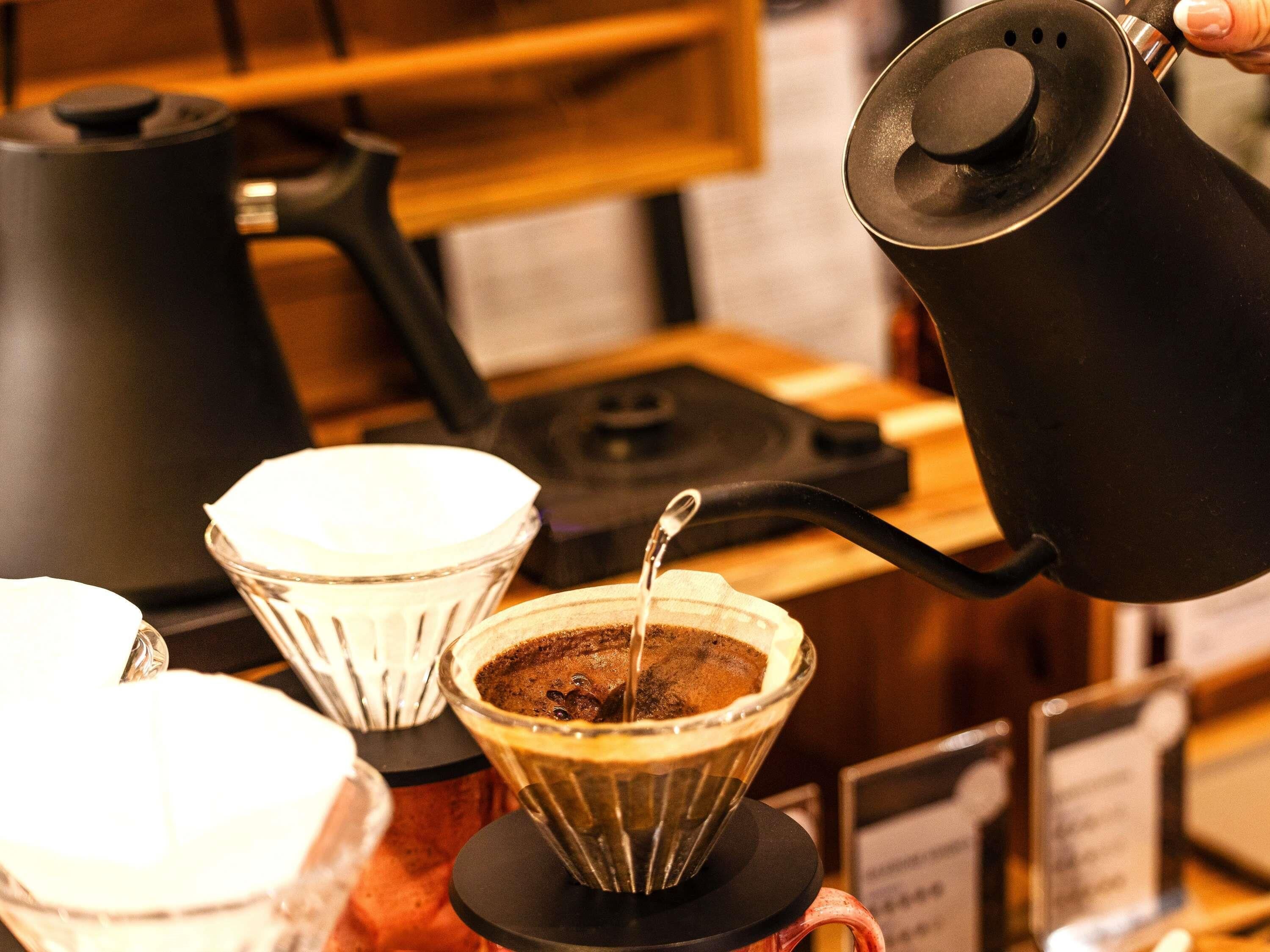 A coffee brewing station with a coffee pot, a drip coffee maker, and a coffee filter.