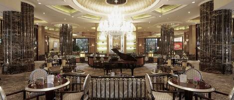 Eine luxuriöse Lobby mit einem Flügel, stilvoller Sitzgelegenheiten und einem Chandelier.