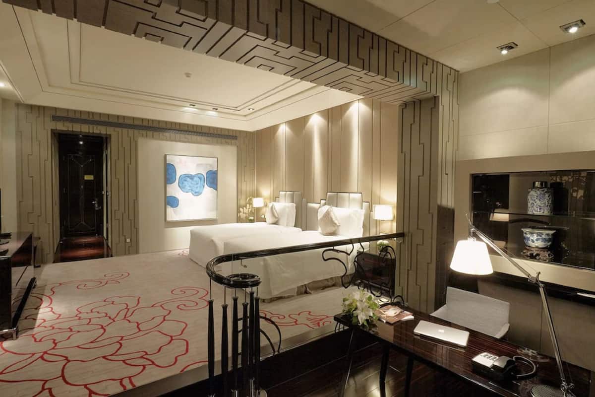 Een hotelkamer met een bed, nachtkastjes, een bureau, een lamp, een schilderij en een spiegel.