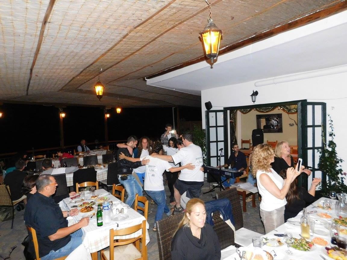 A restaurant with outdoor seating, tables with white tablecloths, and hanging lantern-style lights.