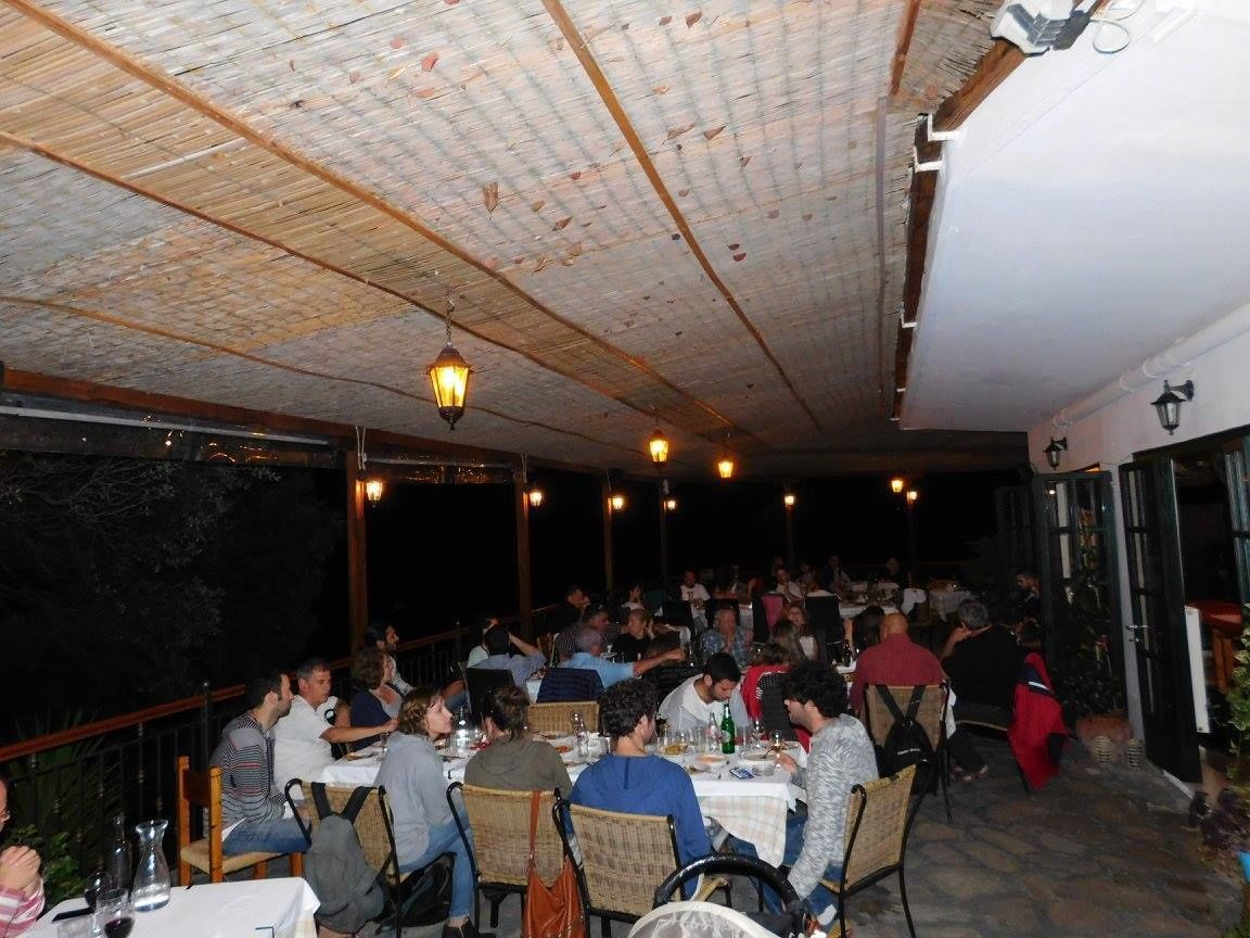 An outdoor dining area with tables and chairs, a wooden ceiling, and hanging lights.