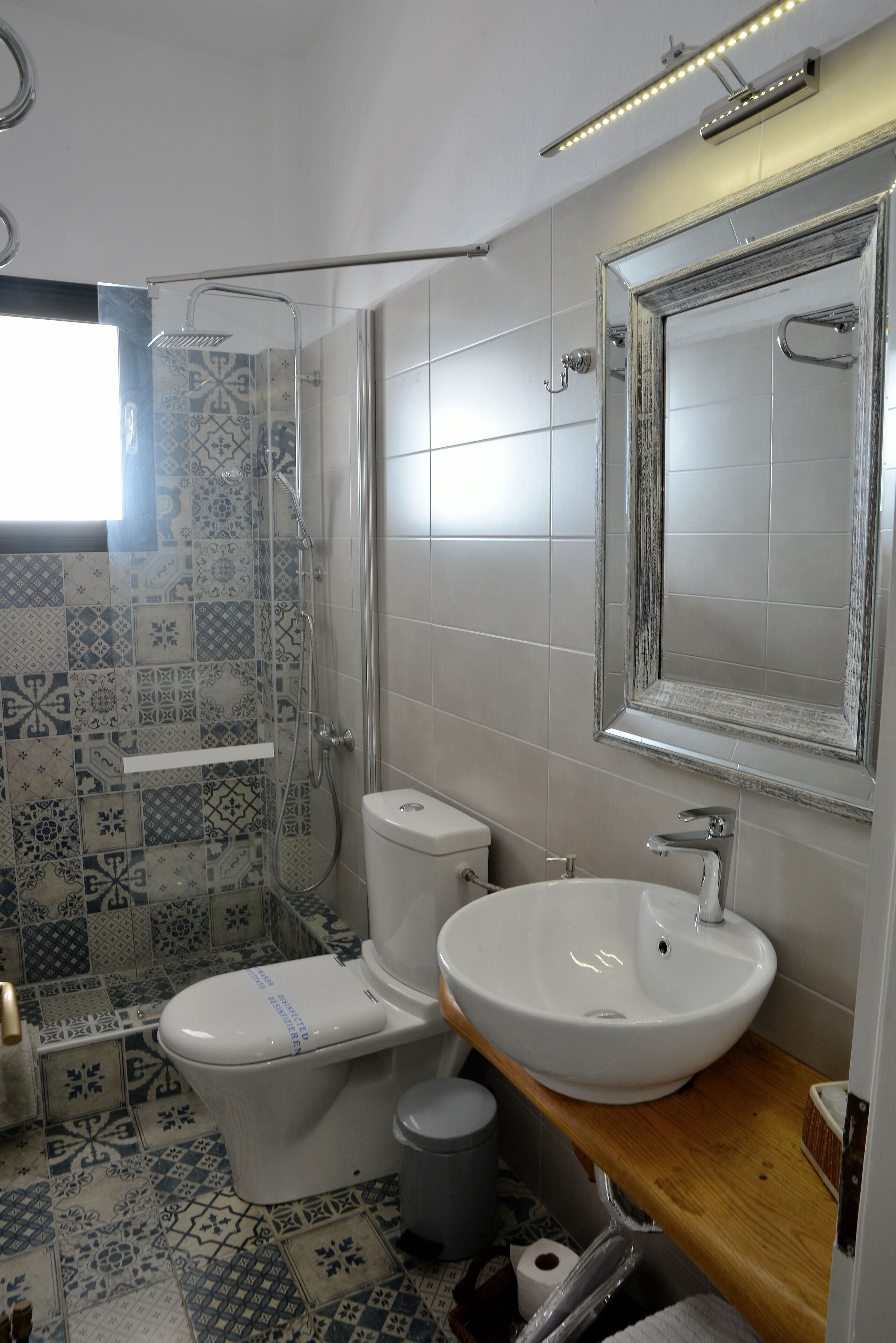 Ein Badezimmer mit Dusche, Toilette, Waschbecken und Spiegel.