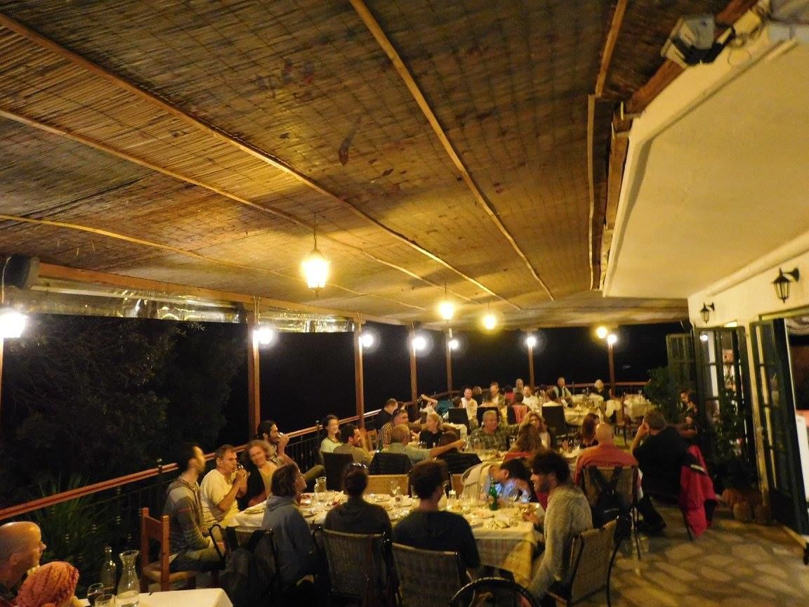 An outdoor dining area with tables and chairs, a wooden ceiling, and hanging lights.
