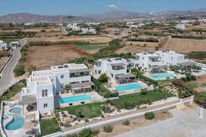 A residential area with modern white houses, a swimming pool, and a road. - Sea & Olives Holiday Villas and Suites (Naxos)