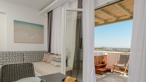 Un balcón con vistas, una mesa de comedor con aperitivos, un sofá y un cuadro en la pared.