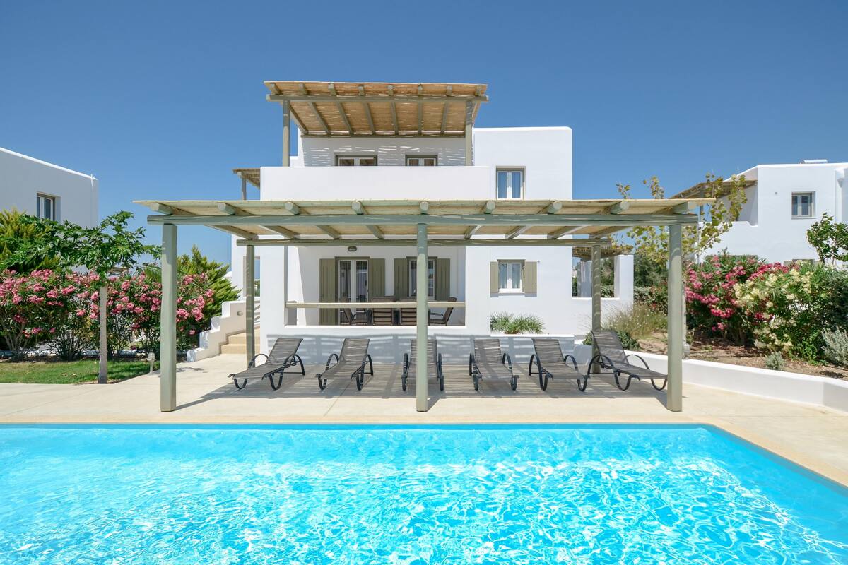 Ein moderner Poolbereich mit einer Pergola, Liegestühlen und einem klaren, blauen Pool.