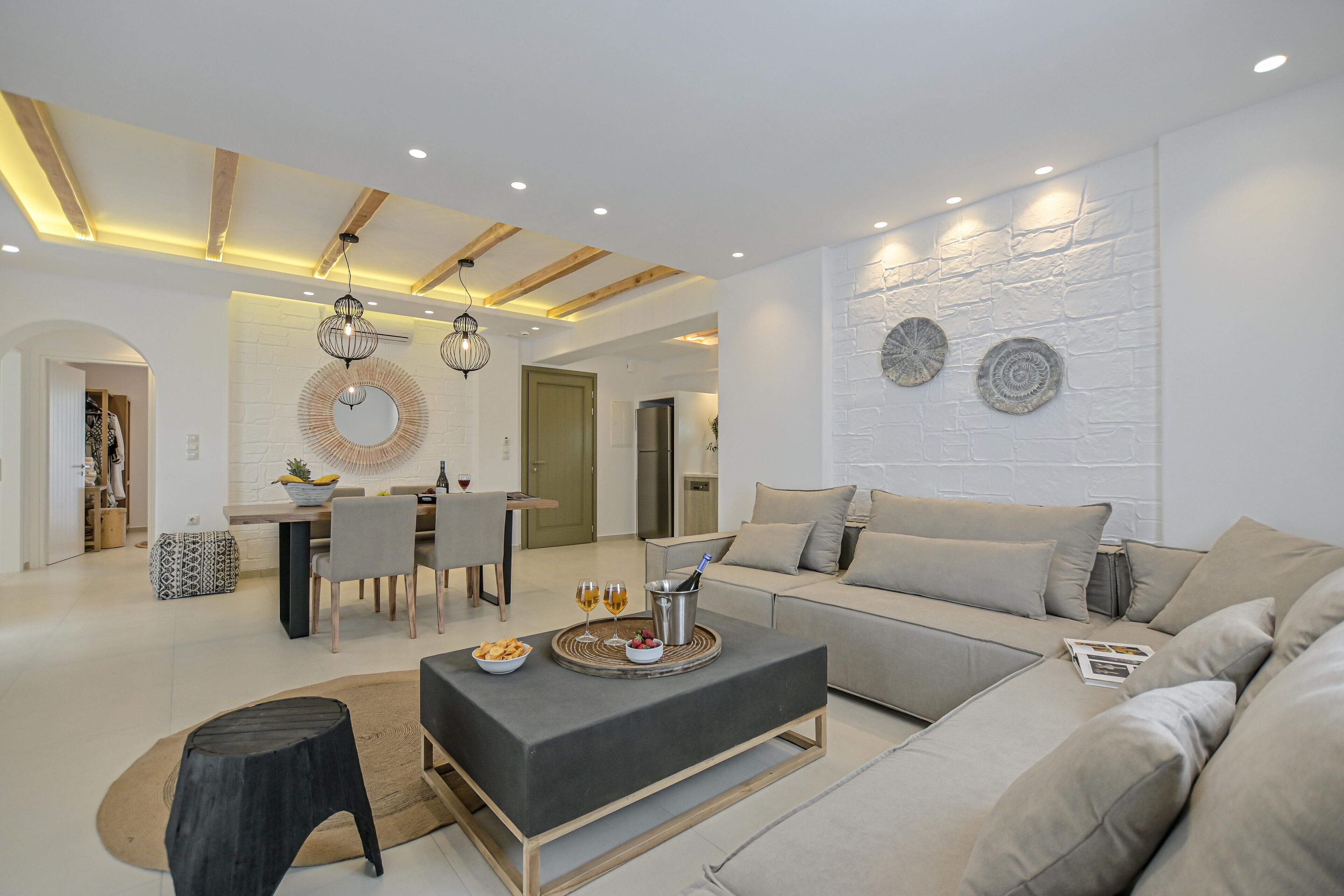A modern living room with a sofa, a coffee table, and a dining area with chairs and a table.