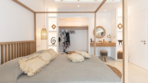Un dormitorio moderno con una cama grande, vigas de techo de madera, un armario y una cómoda con espejo.