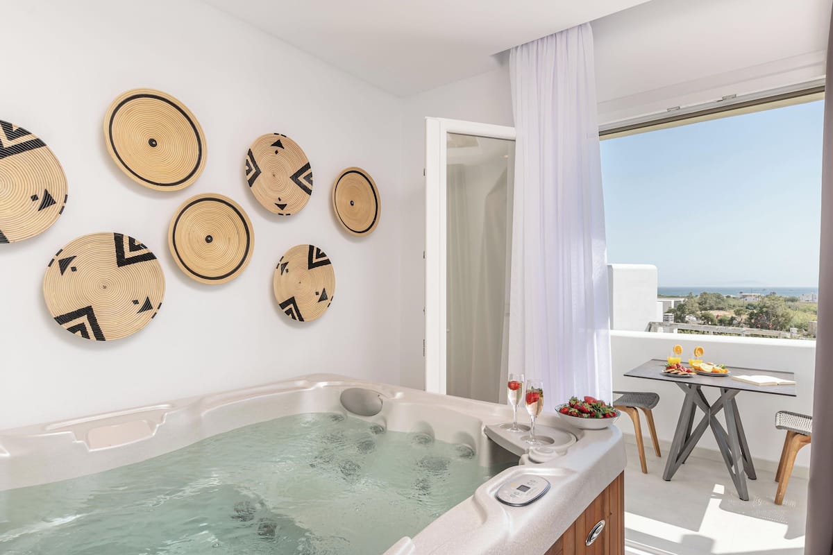 Ein modernes Badezimmer mit Whirlpool, einem Esstisch mit Aussicht und dekorativer Wandkunst.