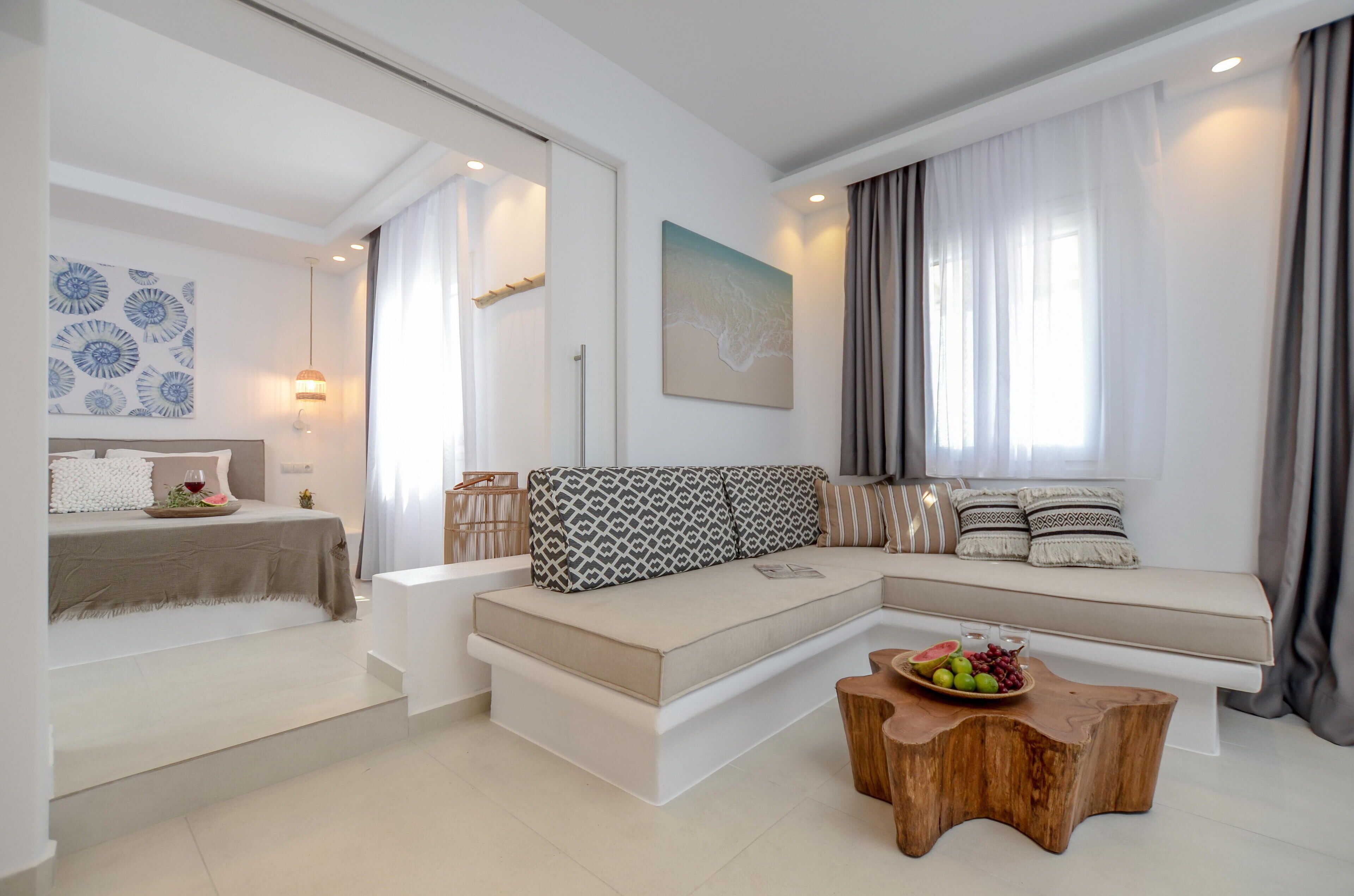 Ein modernes Wohnzimmer mit einem Ecksofa, einem Couchtisch aus Holz und einem Essbereich mit Tisch für zwei Personen.