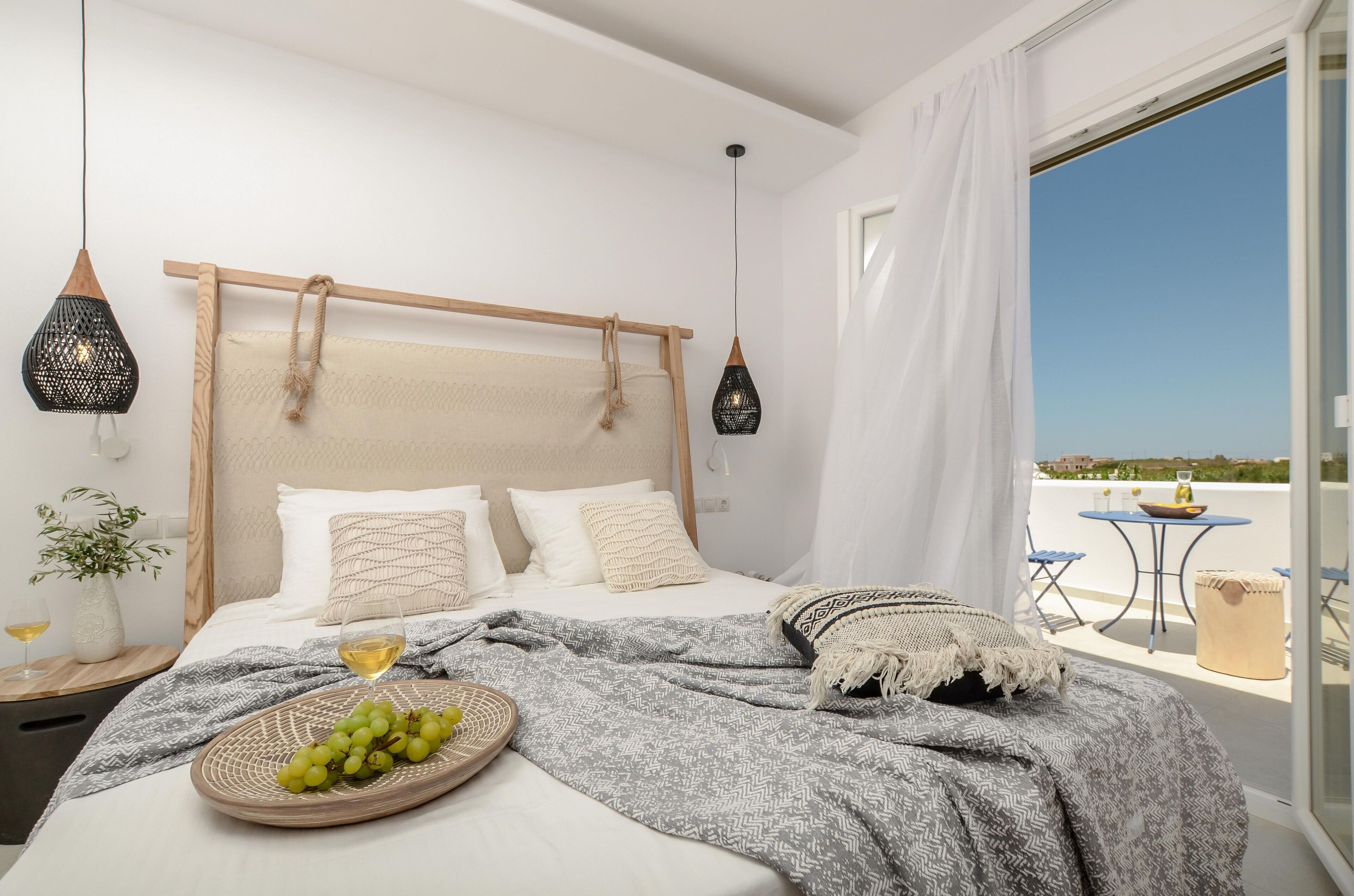 A bedroom with a bed, bedside table, and a view of the outside.