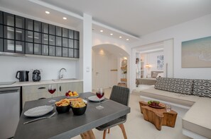 A modern kitchen with a dining area, featuring a grey table, black bowl, and wine glasses. - Sea & Olives Holiday Villas and Suites (Naxos)