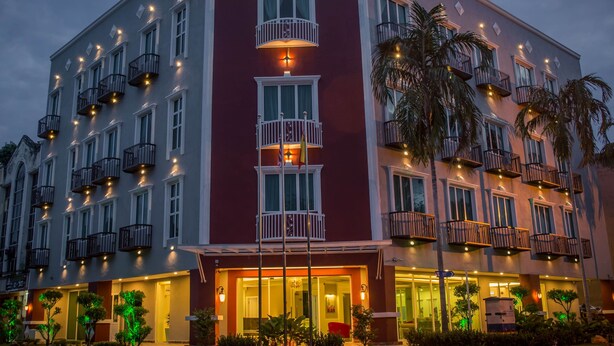 A multi-story hotel with balconies, a prominent sign, and well-lit entrance.