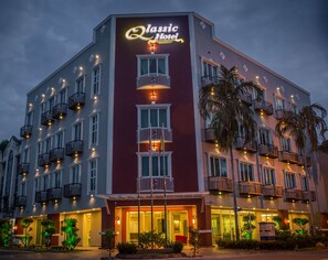 Un hotel de varios pisos con balcones, un cartel llamativo y una entrada bien iluminada.