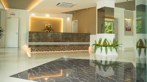 A hotel reception area with a marble reception desk, a tiled wall, and a black marble floor.