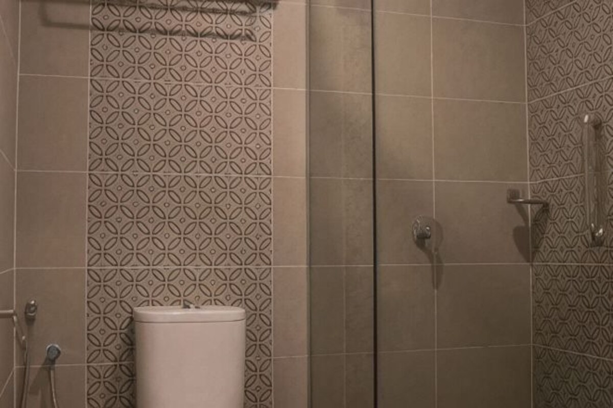A bathroom with patterned tiles, a toilet, and a shower area.