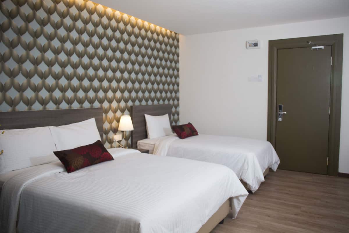 Quarto de hotel com duas camas, parede estampada, assoalho de madeira e uma porta.