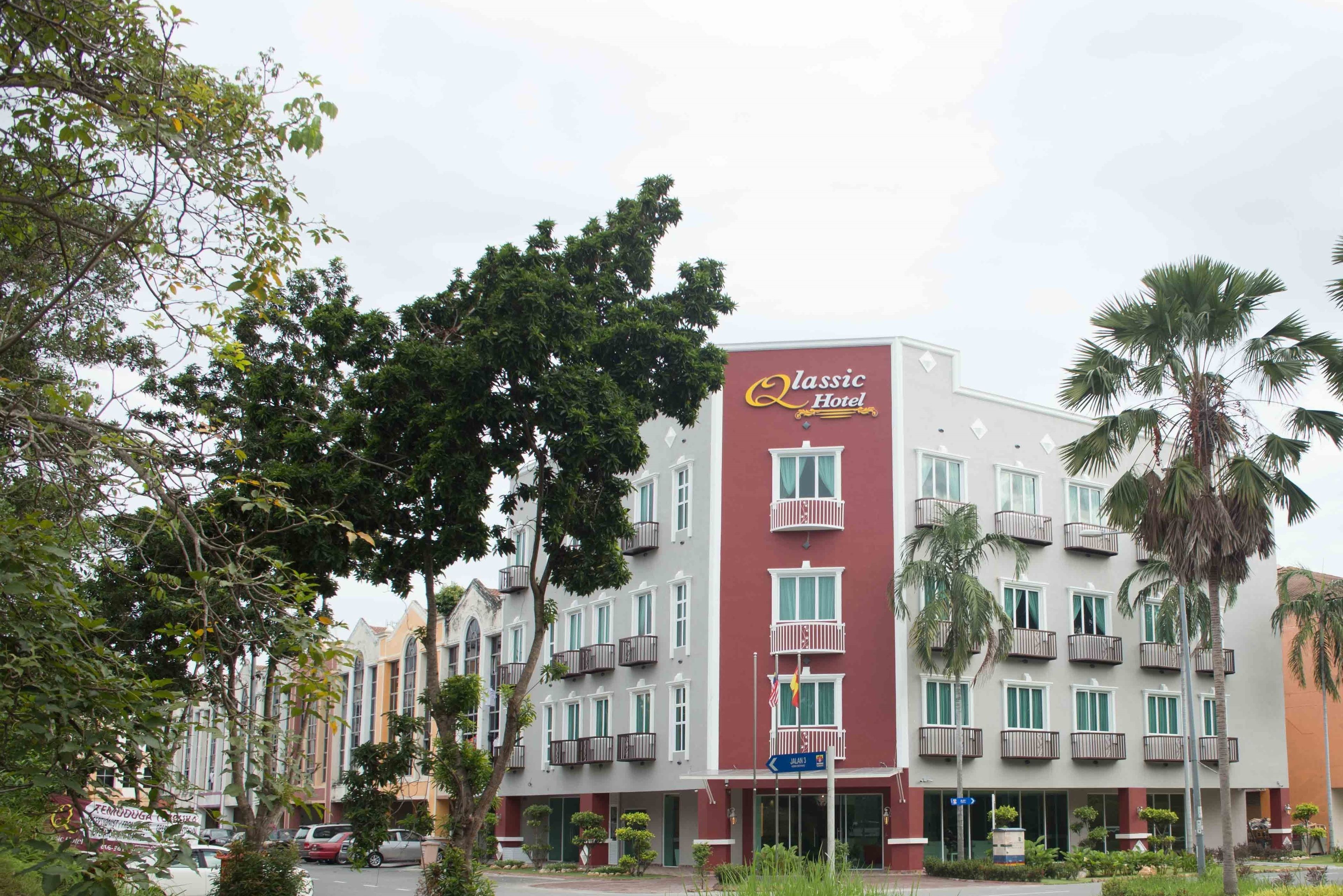 A multi-story hotel with balconies, a prominent sign reading "Classic Hotel," and a street view with parked cars and trees.