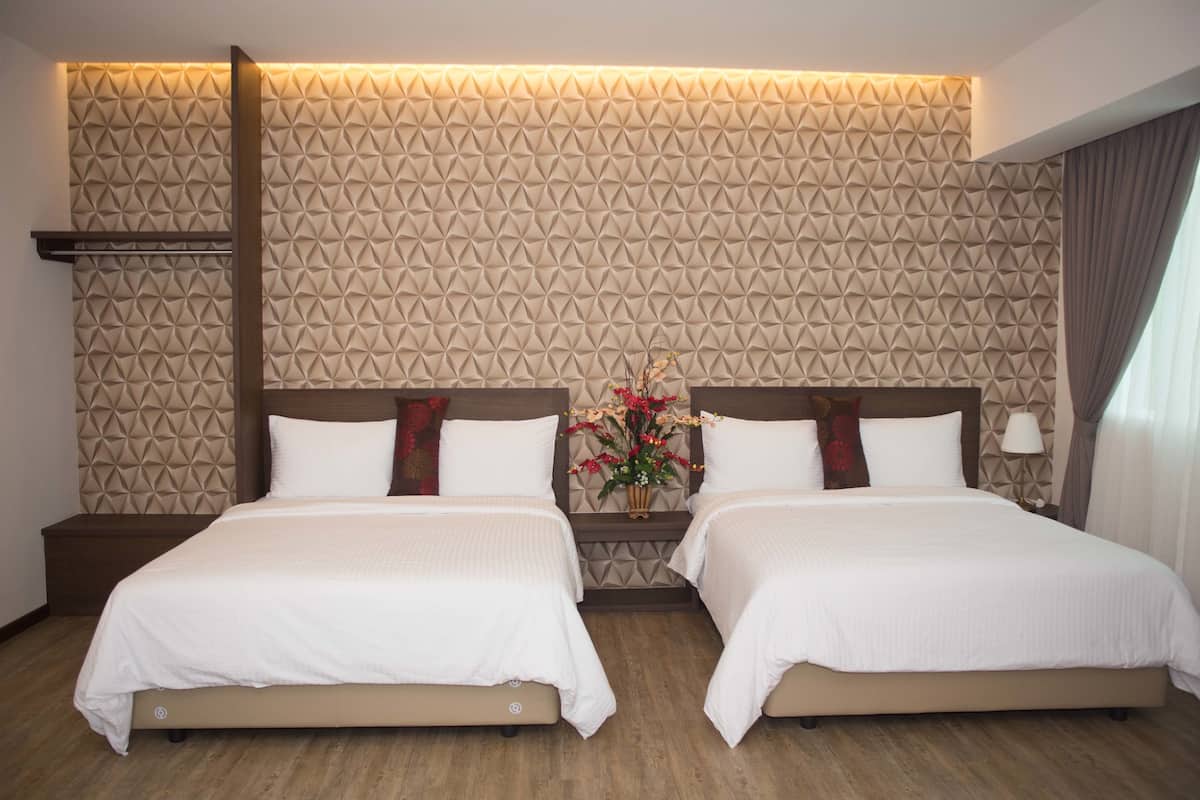 Quarto de hotel com duas camas, um painel decorativo, uma mesa de cabeceira e um vaso com flores.