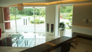 A modern kitchen with a marble countertop, a built-in phone, and a view of a garden through glass doors.