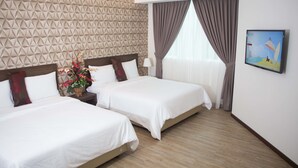 A hotel room with two beds, a decorative wall, a window with curtains, and a welcome sign.