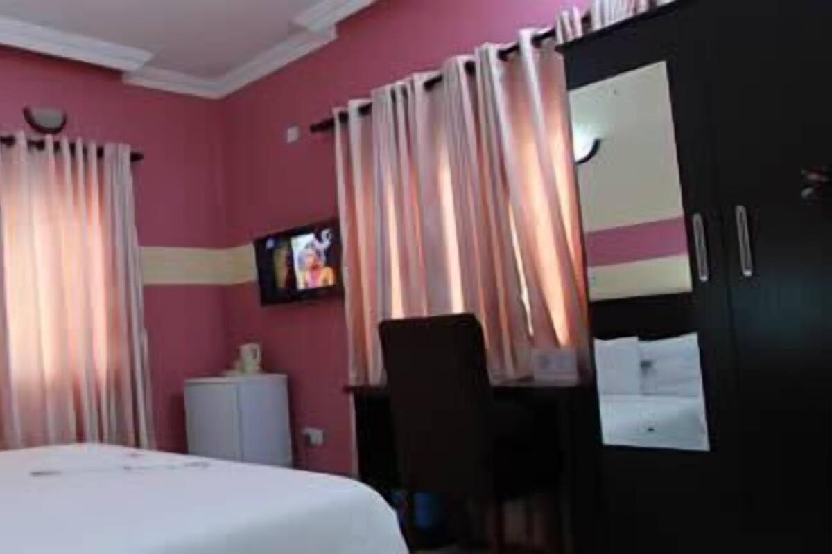 Una habitación de hotel con cama, cortinas, televisor, escritorio y armario.